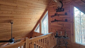 Ein Interieur einer Holzhütte mit Deckenventilator, montiertem Hirschgeweih und einem Tisch mit Flaschen.