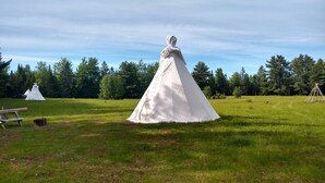 A tent-like structure in a grassy field with trees in the background. - North Woods 12' Teepee Resort (Exeter)