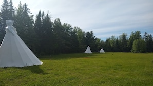 A grassy field with three white tents. - North Woods 12' Teepee Resort (Exeter)