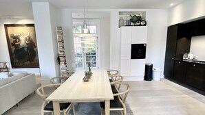 A modern kitchen with a dining area, featuring a long wooden table, chairs, and a built-in oven. - Spacious luxury apartment in city Center . (Copenhagen)