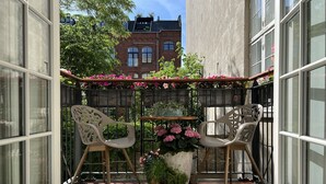 A balcony with two chairs, a potted plant, and a small table. - Spacious luxury apartment in city Center . (Copenhagen)