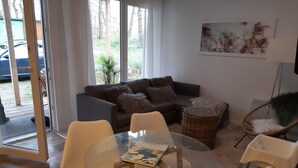Un salon avec une table en verre, un canapé et un panier en osier.