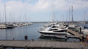 Un port de plaisance où sont amarrés de nombreux bateaux, une jetée en bois et une côte rocheuse.