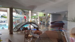 Un espace piscine doté d’un pont de verre, de chaises longues et d’une table à manger.