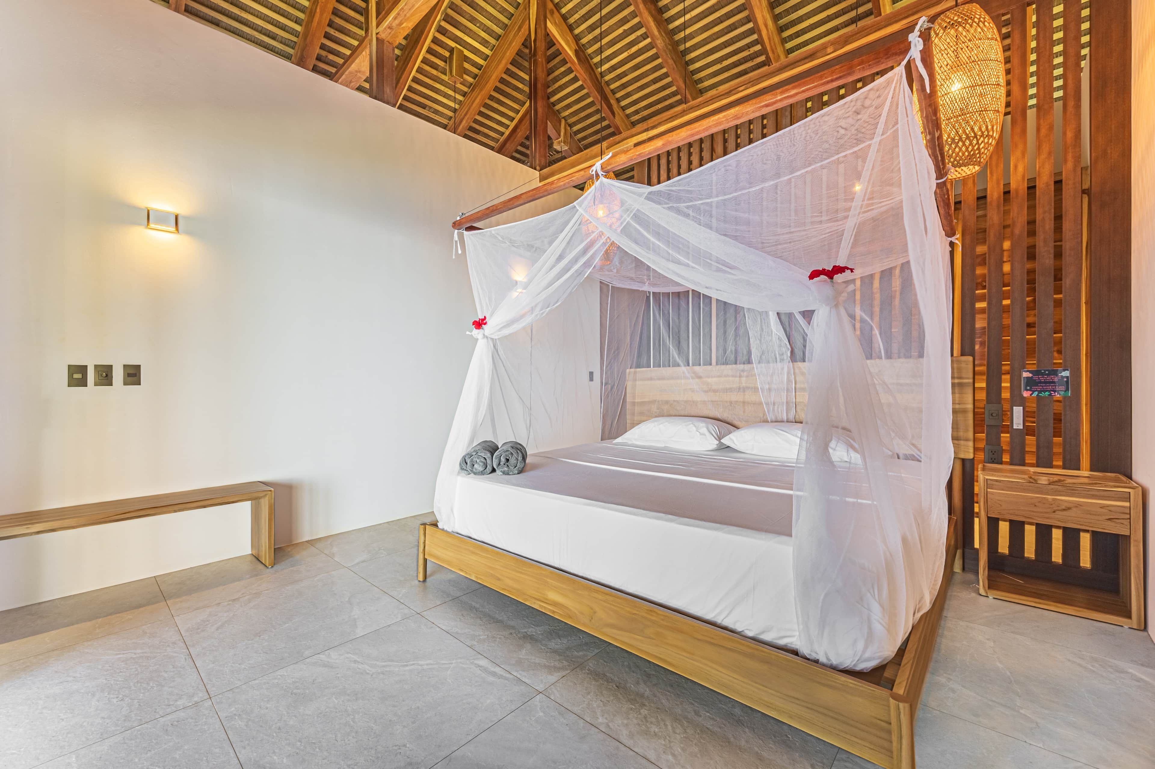 Een slaapkamer met een houten bedframe, witte beddengoed en een hemelbed.