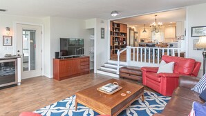 Un salon moderne avec une table basse en bois, un canapé en cuir rouge et un téléviseur posé sur un meuble en bois.