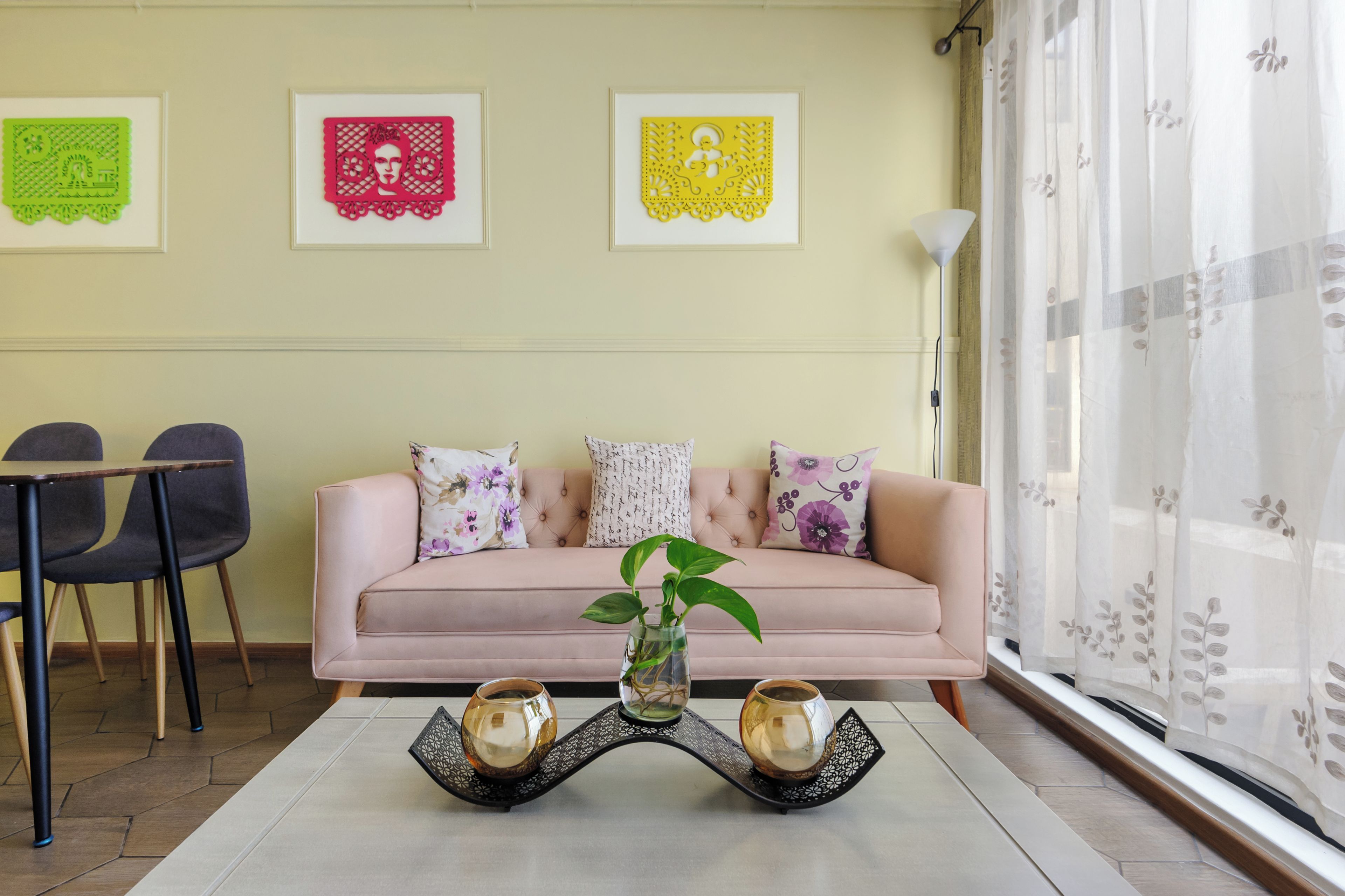 Ein Wohnzimmer mit einer Couch, Sesseln, einem Couchtisch mit zwei Vasen und drei gerahmten Kunstwerken an der Wand.
