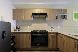 A modern kitchen with wooden cabinets, a built-in microwave, a gas stove, and a coffee maker.