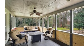 Relax on the covered porch with a ceiling fan overhead, two sofas, and a small table.