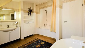 A modern bathroom with a large bathtub, a separate shower area, and a vanity with a mirror and sink. - Ferienwohnung Meerblick - Penthouse, Dachterrasse, Meerblick, Strand (Binz)