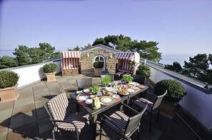 Un patio al aire libre con una mesa lista para comer, rodeado de sillas de mimbre y toldos a rayas.