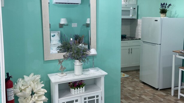 Een keuken met blauwgroene wanden, witte kasten en een witte koelkast.