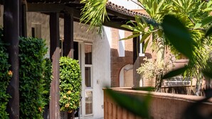 A courtyard with a pergola, potted plants, and a wooden fence. - Casa Sunzal Boutique Hotel (Tamanique)