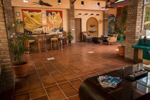 A spacious indoor area with a tiled floor, wooden furniture, and potted plants.