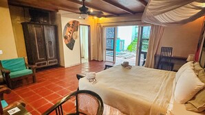 A hotel room with a bed, a desk, a chair, a table, a ceiling fan, and a view of the outdoors. - Casa Sunzal Boutique Hotel (Tamanique)