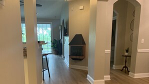 A spacious hallway with a fireplace, a dining area, and a view of the outdoors.