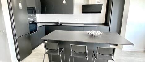 A modern kitchen with a central island, bar stools, and a built-in oven.
