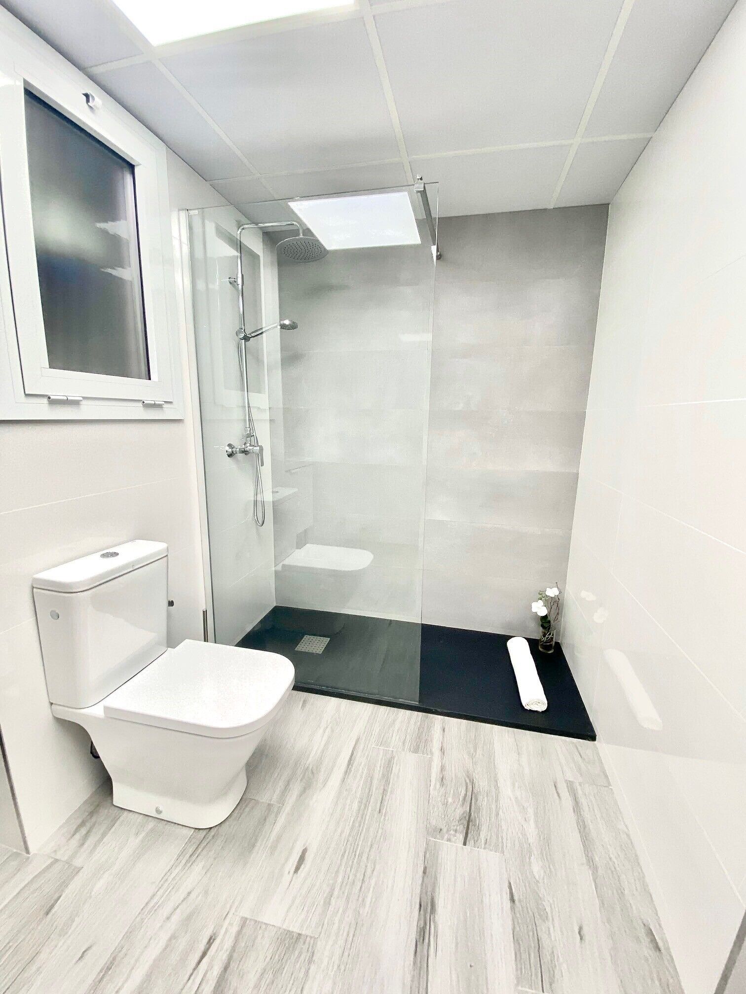 Un baño moderno con inodoro, ducha y lavamanos.