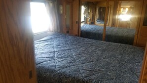 A compact RV interior with two beds, a window, and wooden walls. - Montana Mountain Memories- RV in Orchard by Trout Pond (Florence)