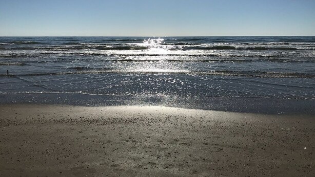 Una spiaggia con onde e cielo sereno.