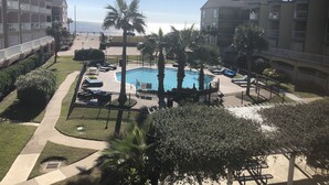 Area piscina con palme, lettini e vista libera sull'oceano.