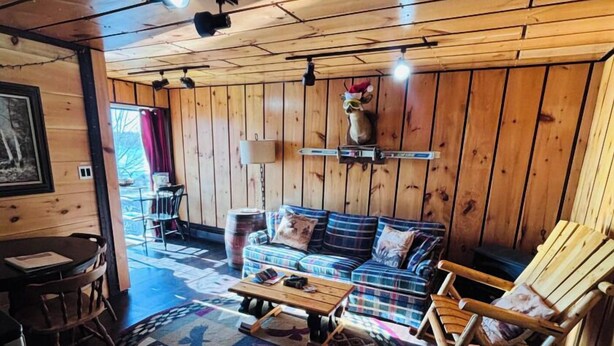 A wooden interior with a sofa, rocking chair, and a patterned rug. - Lake Side Guest Suite (Hermon)