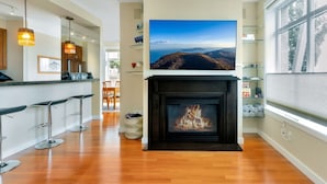 A modern kitchen with a fireplace, wooden flooring, and a large window. - Waterfront 2BD Next to Pike Place w/ Private Patio (Seattle)