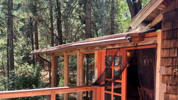Eine Holzterrasse mit Geländer, einem Stuhl und einem Tisch.