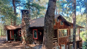 Ein rustikales Blockhaus mit Steinkamin, Holzfassade und roten Akzenten.
