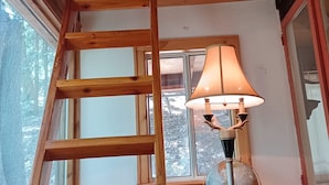 Ein Holzinnenraum mit einem Schlafmaßwerk, einer Himmelsleiter, einem Globus und einer Lampe.