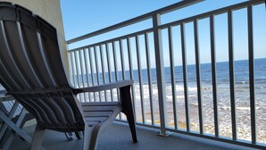 Een balkon met een metalen hekwerk dat uitkijkt over een strand.