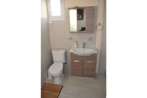 Een bad/douchecombinatie, handdoeken, toiletpapier
