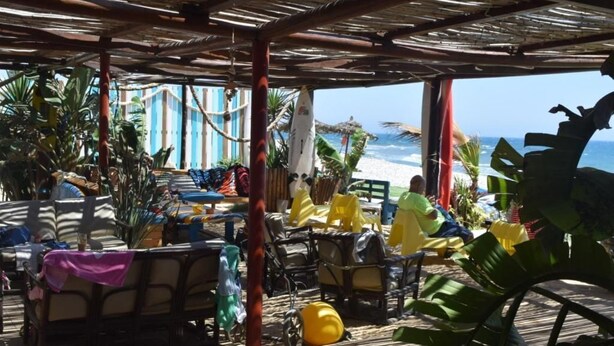 Een terras met tafels en stoelen, met uitzicht op de oceaan.