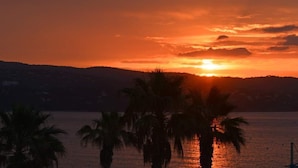 A sunset over a body of water with palm trees in the foreground. - Studio Avec Clim et Parking Privėe (Cavalaire-sur-Mer)
