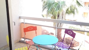 A balcony with a blue table and four chairs, one of which is purple. - Studio Avec Clim et Parking Privėe (Cavalaire-sur-Mer)