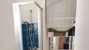 A bathroom with a glass-enclosed shower, a white toilet, and a mirror above the sink. - Studio Avec Clim et Parking Privėe (Cavalaire-sur-Mer)