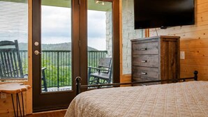 Una camera da letto con un letto, una cassettiera, una TV e un balcone con vista.