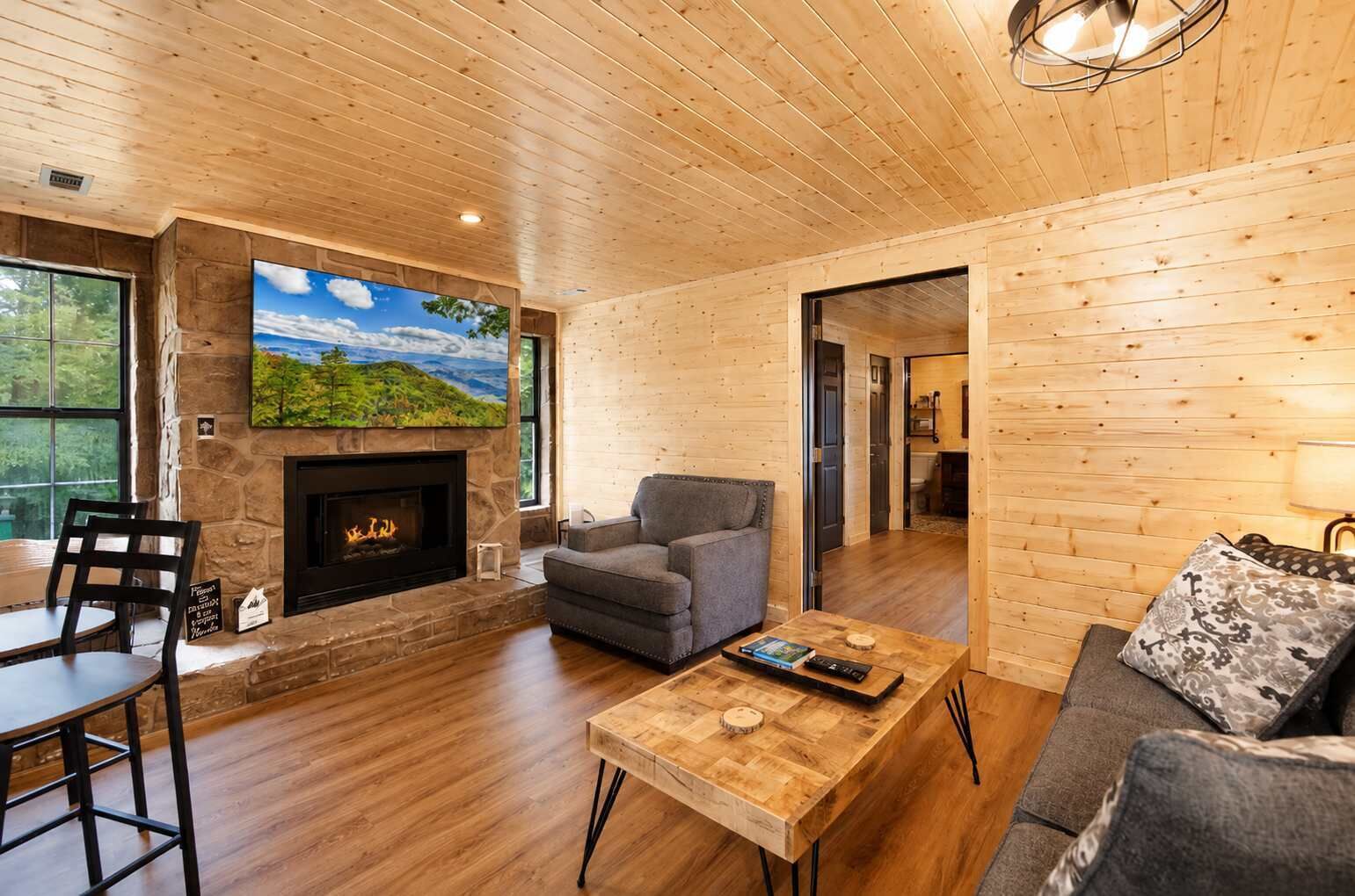 A wooden interior with a fireplace, a sofa, a coffee table, and a dining area.