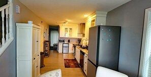 Una cocina estrecha con muebles blancos, un refrigerador y un microondas.