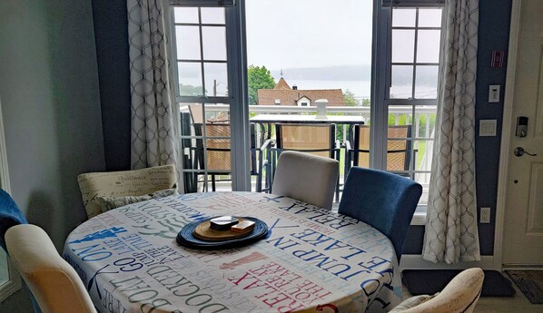 Un comedor con una mesa redonda, sillas y vista a un edificio desde un balcón.