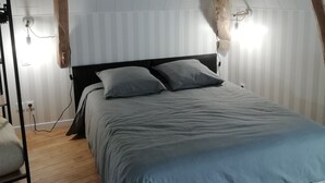 Ein Schlafzimmer mit Holzboden, einem Bett mit grauer Bettwäsche und einem Nachttisch.