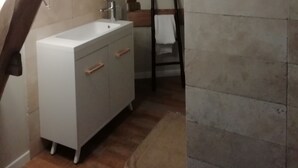Ein kleines, schmales Schlafzimmer im Dachgeschoss mit einem weißen Schminktisch, einer Holzleiter und einem Fliesenboden.