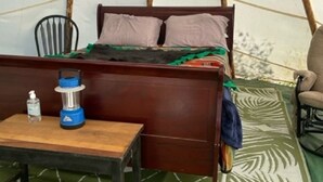 Ein Zimmer mit einem Bett, einem Tisch und einer Wasserflasche sowie einem Stuhl.