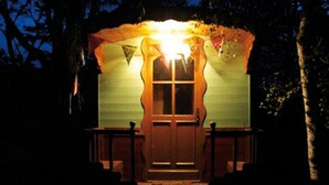 Eine Holzhütte mit Eingangstür und kleiner Veranda, umgeben von Bäumen.