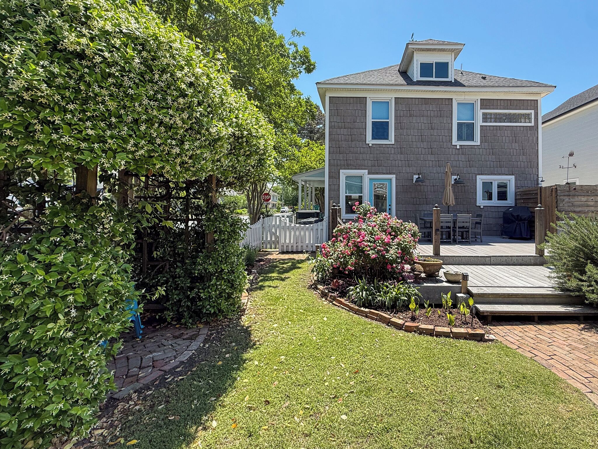 A two-story house with a covered patio, a fenced yard, and a stop sign.
