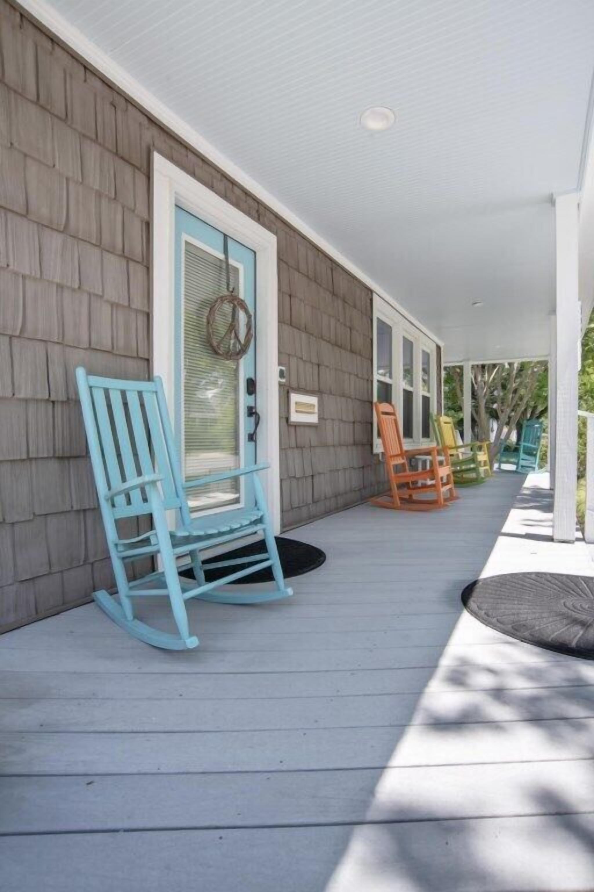 A porch with rocking chairs and a door with a wreath.