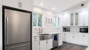 Une cuisine moderne avec des meubles blancs, des appareils en acier inoxydable et un plancher en bois.