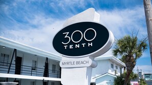 A sign for "300 Tenth Myrtle Beach" with a white building in the background. - 300 Tenth (Myrtle Beach)