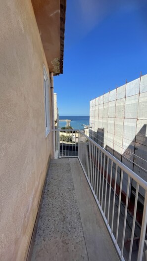 A balcony with a view of the sea and a construction site.