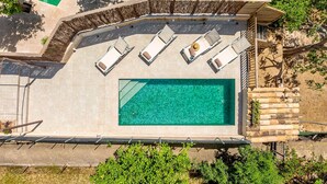Vista aerea di una zona piscina con lettini e un muro in pietra.